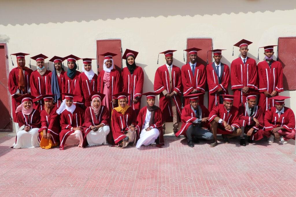 An Abaarso graduating class in red caps and gowns posed in two rows outside the school.