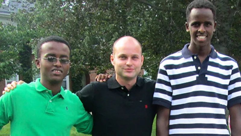 Jonathan Starr standing between two Abaarso students outdoors.