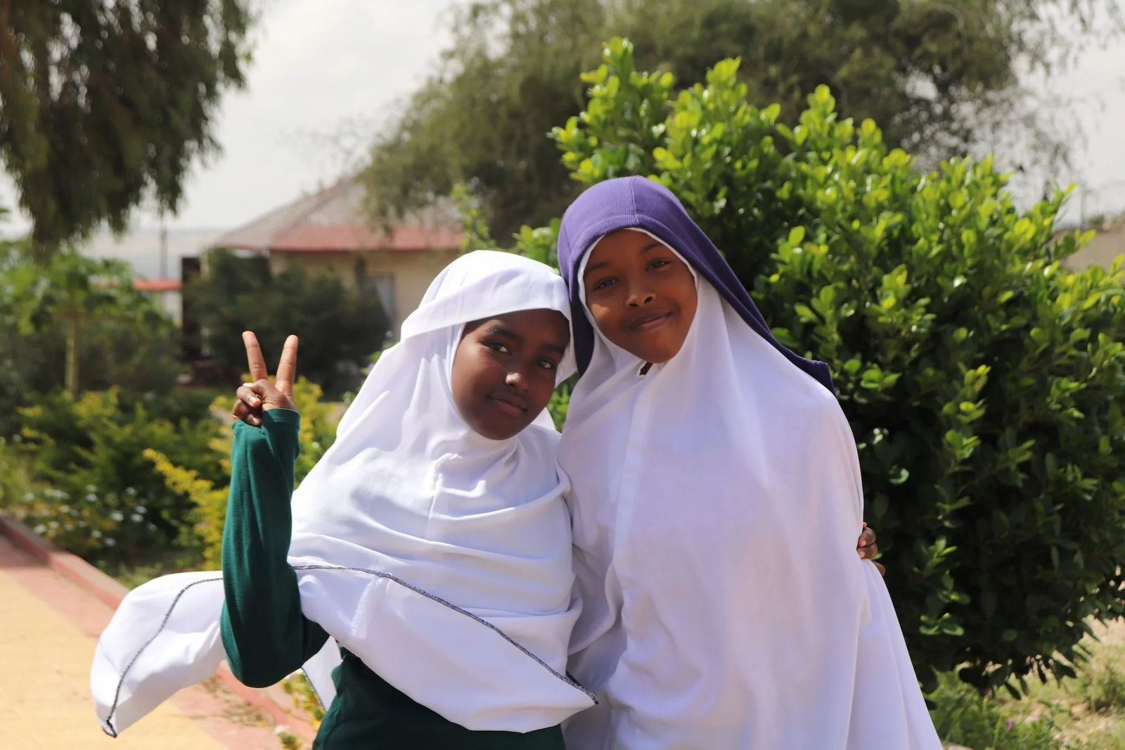 Two Abaarso students smiling outside, one making a peace sign.